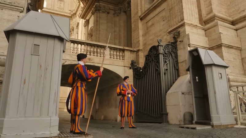 Swiss Guards in their distinctive Renaissance-style uniforms, standing at attention outside the Vatican