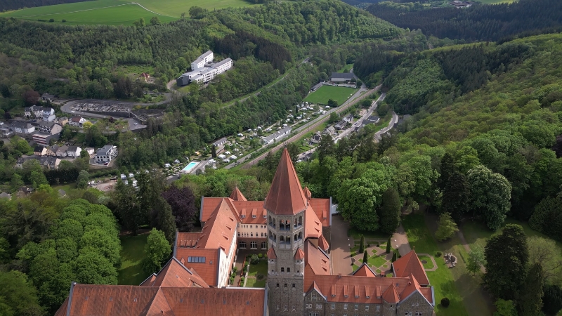An aerial view of a Swiss monastery surrounded by lush greenery and hills